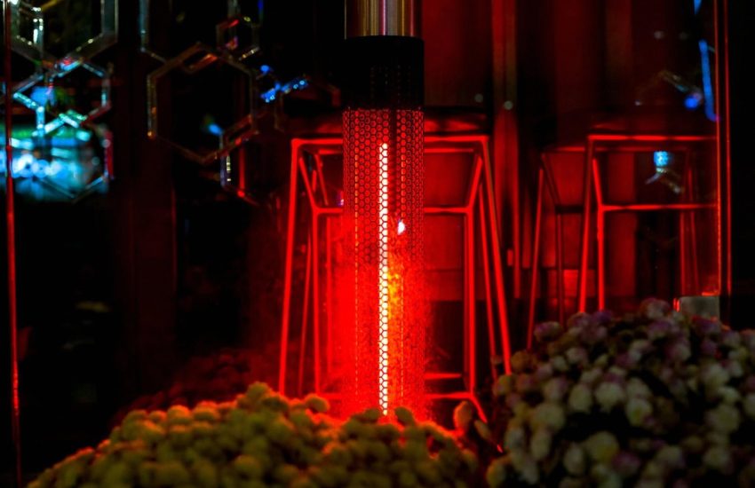 Glowing red outdoor patio heater between seating at a Dubai restaurant terrace at night